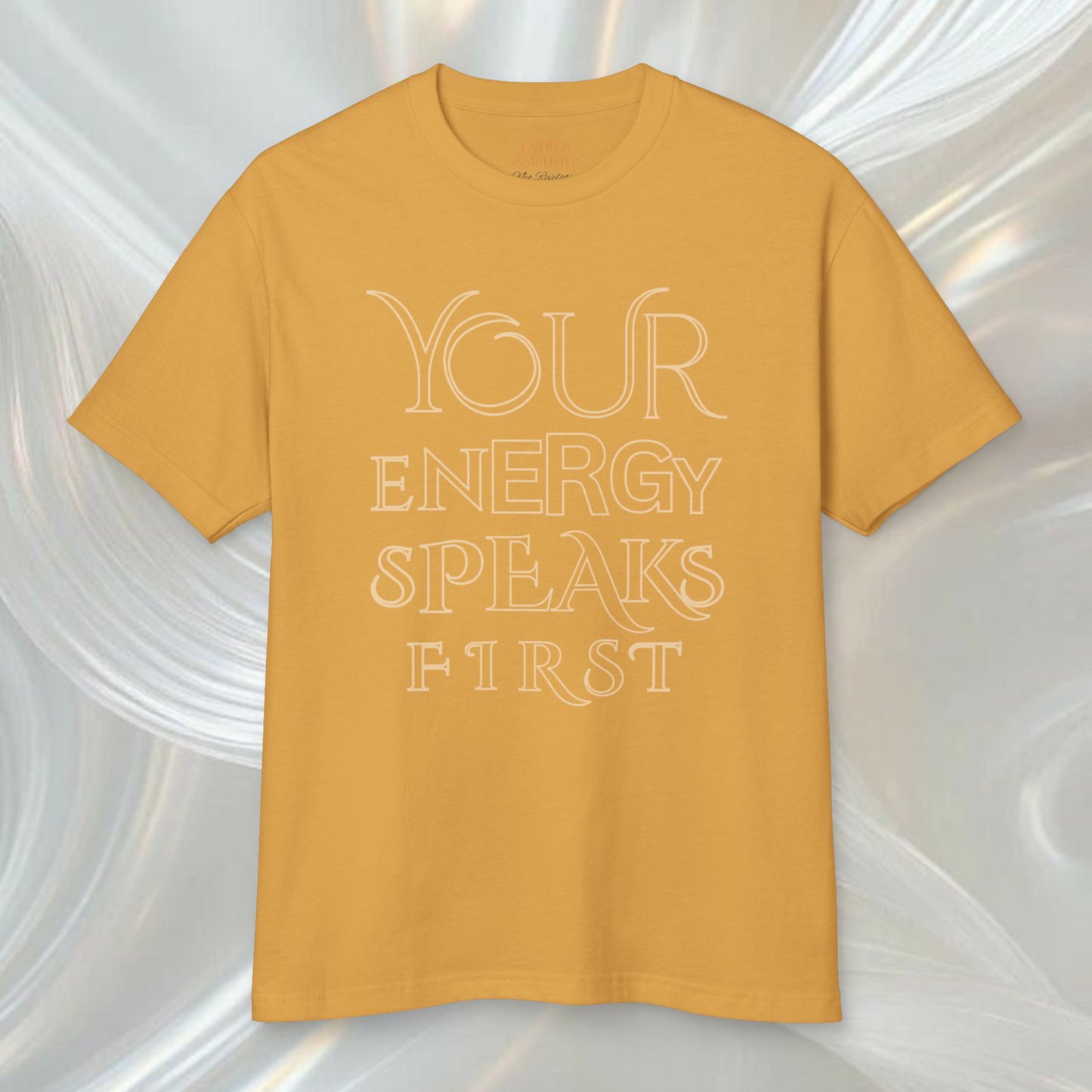 yellow t-shirt 100% organic cotton with the saying ' your energy speaks first' in elegant big and thing letters on a white ethereal spiritual soft background, high vibrational clothes spiritually designed brand innovative concept in fashion