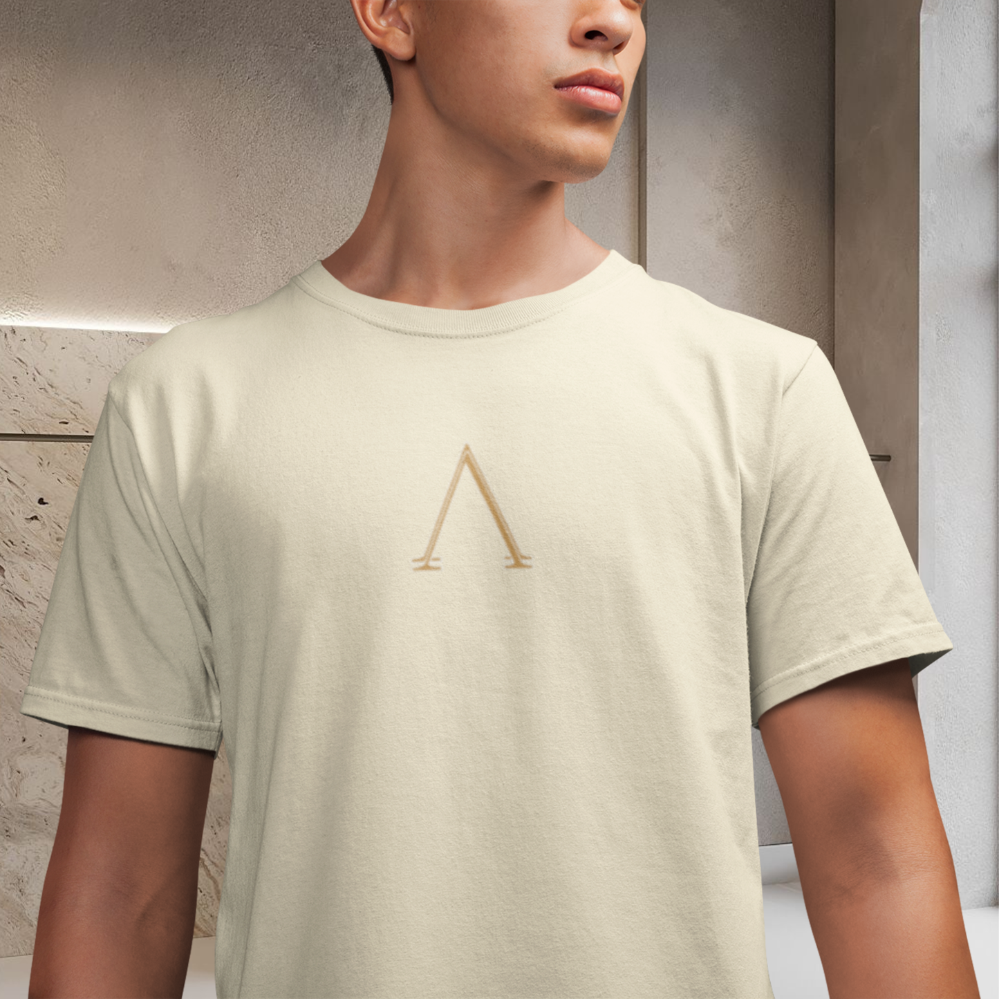 presentation of a white cream color t-shirt 100% cotton wore by a male model face cutted lower body cutted a minimalist symbol on the chest gold color A shape.  spiritually designed t-shirt high vibrational clothing unisex fashion style