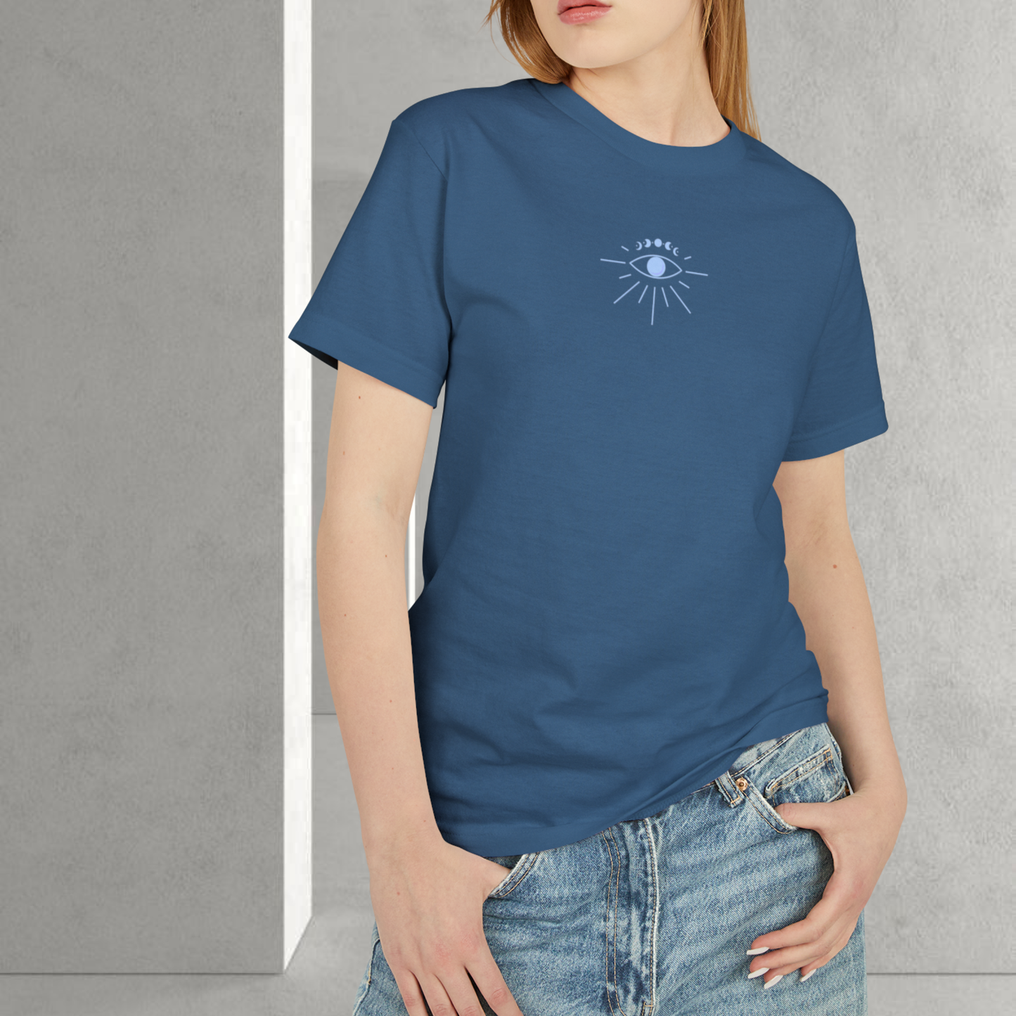 a red head model wearing a faded blue unisex 100% cotton t-shirt and a jeans pants the t-shirt have an consciouness eye graphic on the chest light blue color she have white nail color 