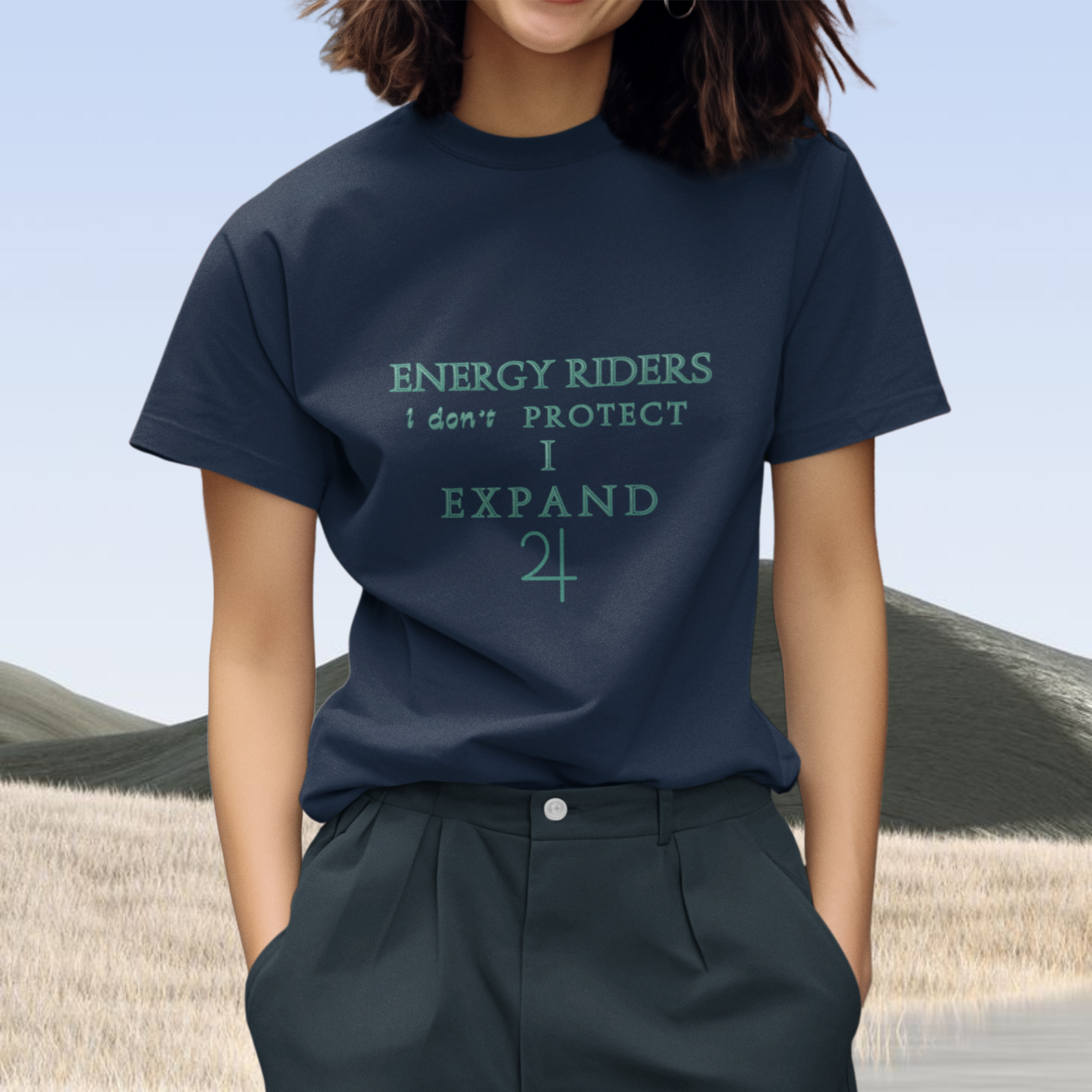 Spiritual clothing energy infused intentional fashion to wear, cotton t-shirt unisex style blue navy color winter 2026 for neo revelation innovative spiritual concept in fashion world , this shirt is printed with jupiter symbol and the statement 'energy riders i don't protect i expand' in turquoi green color  the model standing is brunette standing on a minimalist background landscape sobre style