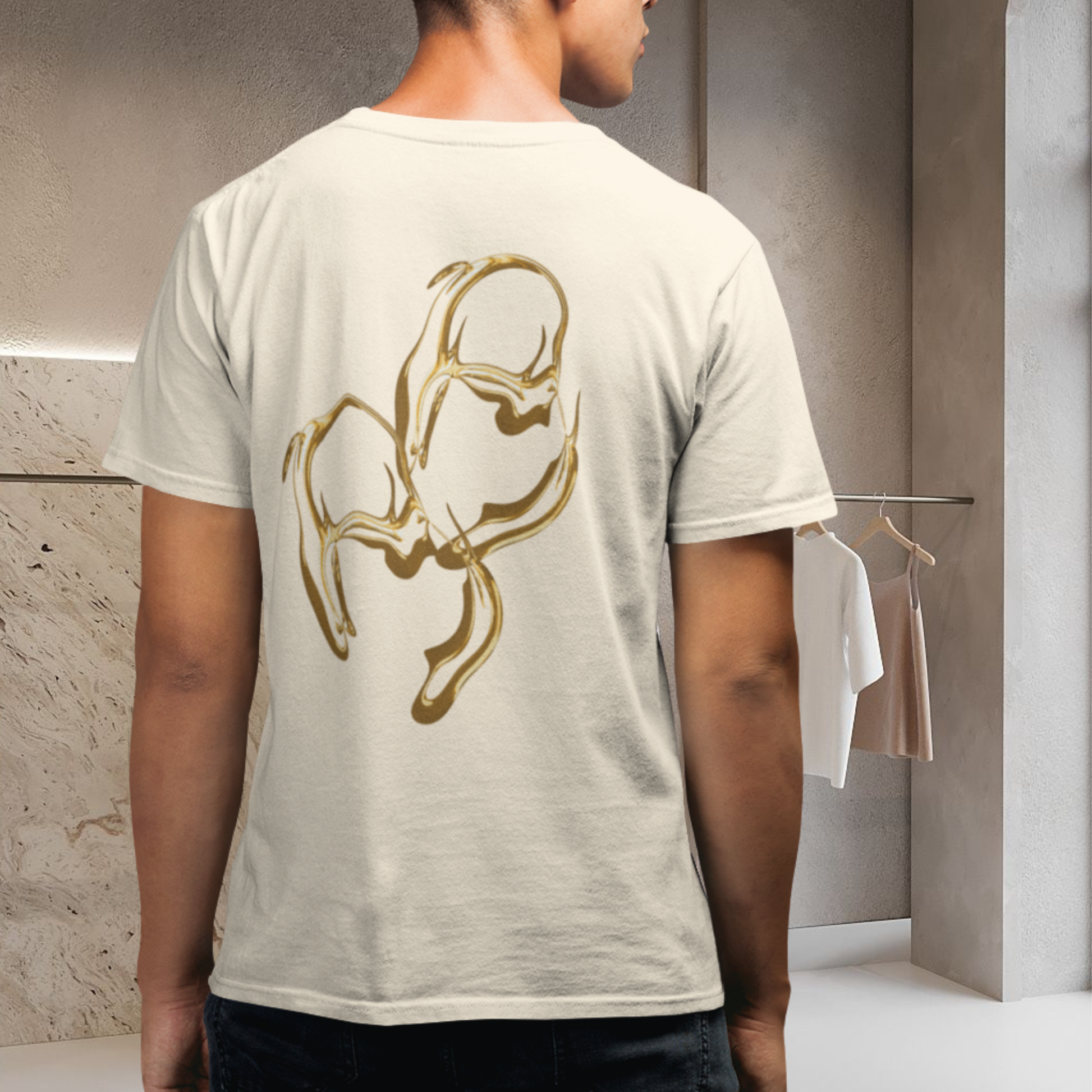 white unisex t-shirt wore by a male model in a changing room , the t-shirt with gold abstract design on the back spiritually designed innovative conceptual graphic energy infused high vibrational grpahic fashion